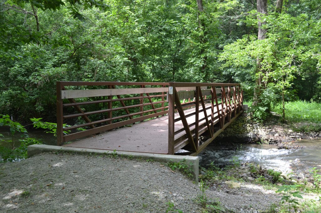 A truss bridge crosses a small stream.